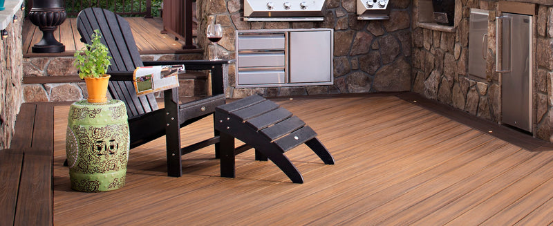 A black Trex Outdoor Furniture Yacht Club Shellback 2 Piece Adirondack Seating Set sits on a deck with stone cabinets.