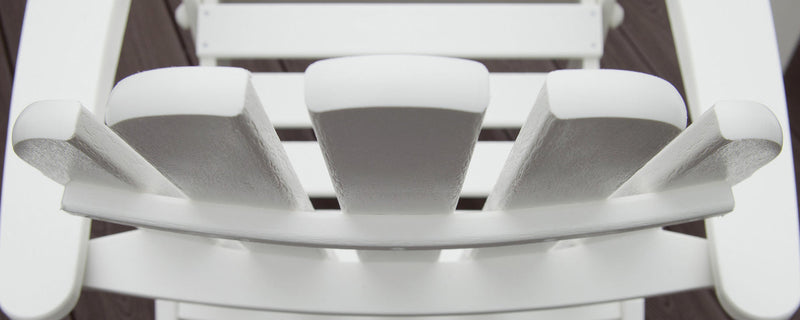 An overhead view shows the top of a white Adirondack chair's headrest, arms, and seat.