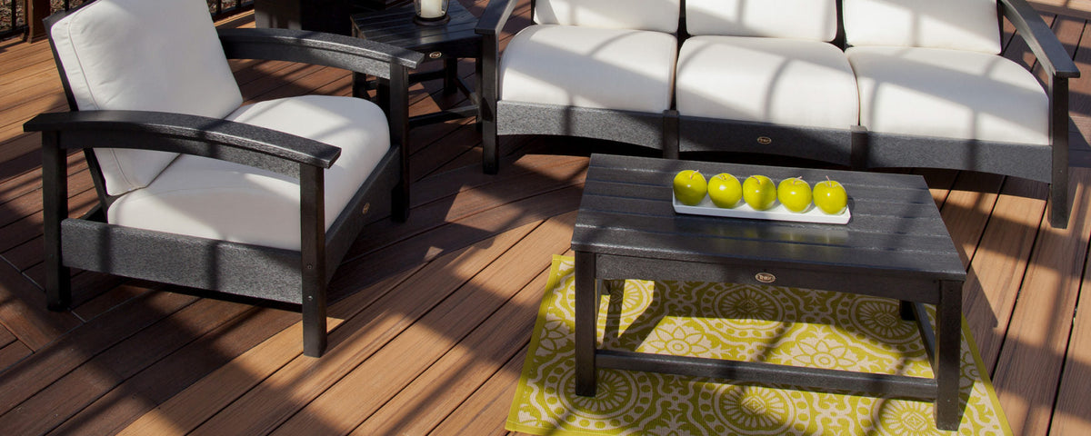 Black Trex Outdoor Furniture Rockport deep seating furniture with white cushions sits on a wooden deck.
